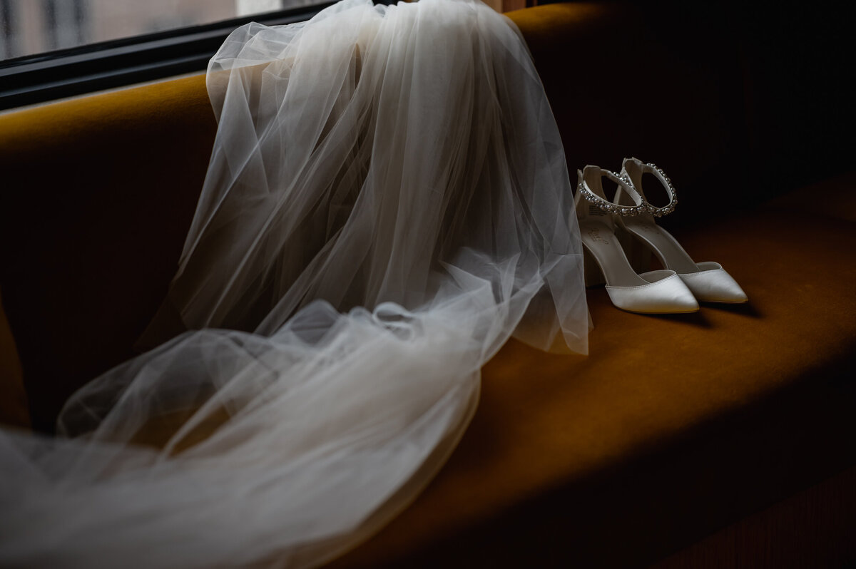 Wedding shoes and a veil sit on a yellow couch