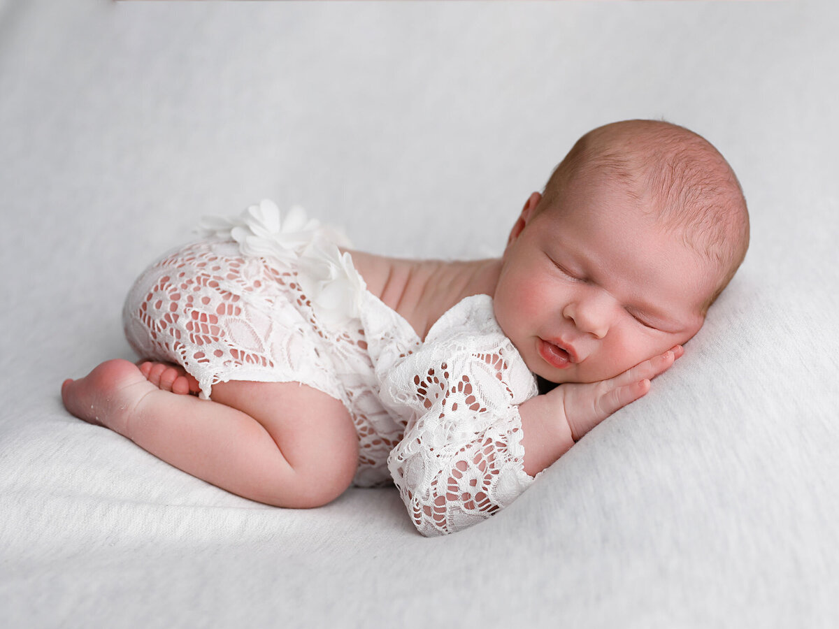 Newborn-photography-session-newborn-in-classic-newborn-photography-pose-with-white-dress-and-headband-photo-taken-by-Janina-Botha-photographer-in-Oakville-Ontario