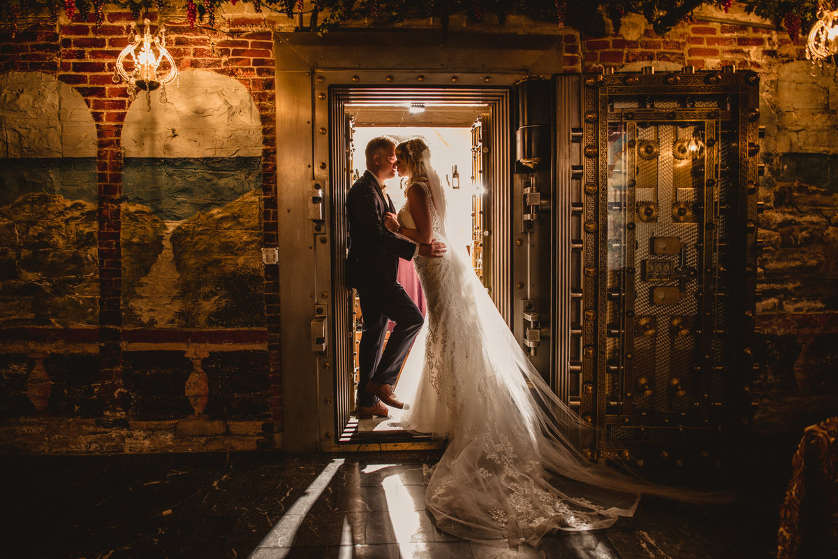 Bride and groom kiss in a wine cellar.