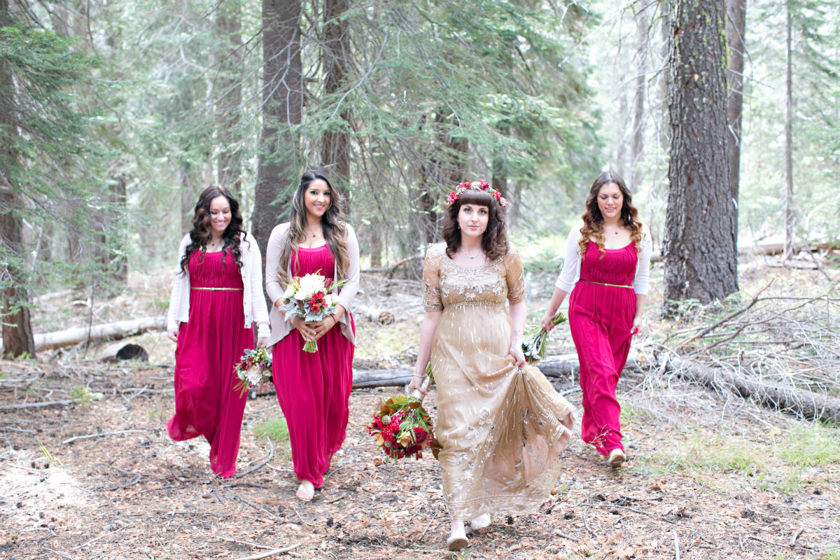 Bride wearing gold wedding dress and bridesmaids walking in the Tahoe forest