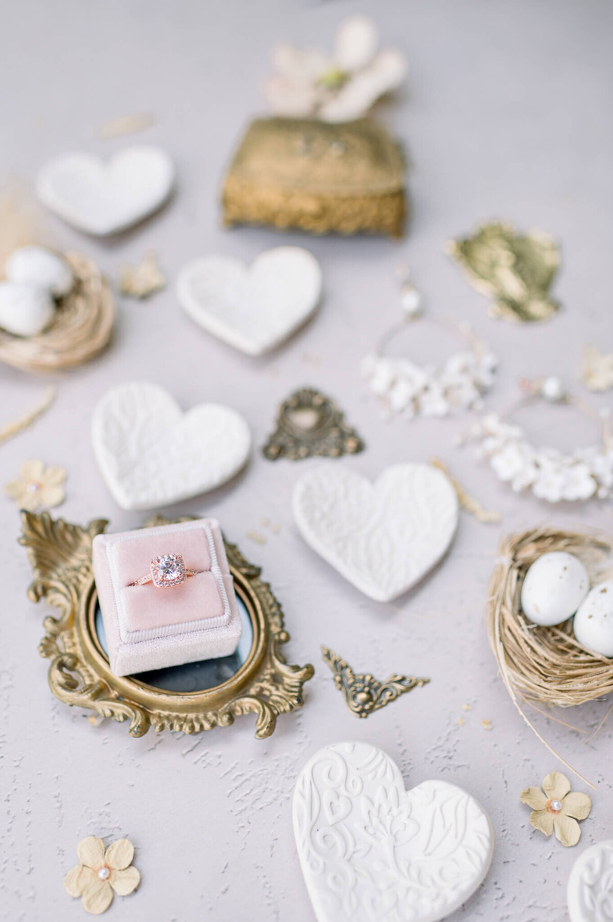 wedding details featuring ring, pink colors, small intricate detailed clay hearts and a nest with two eggs