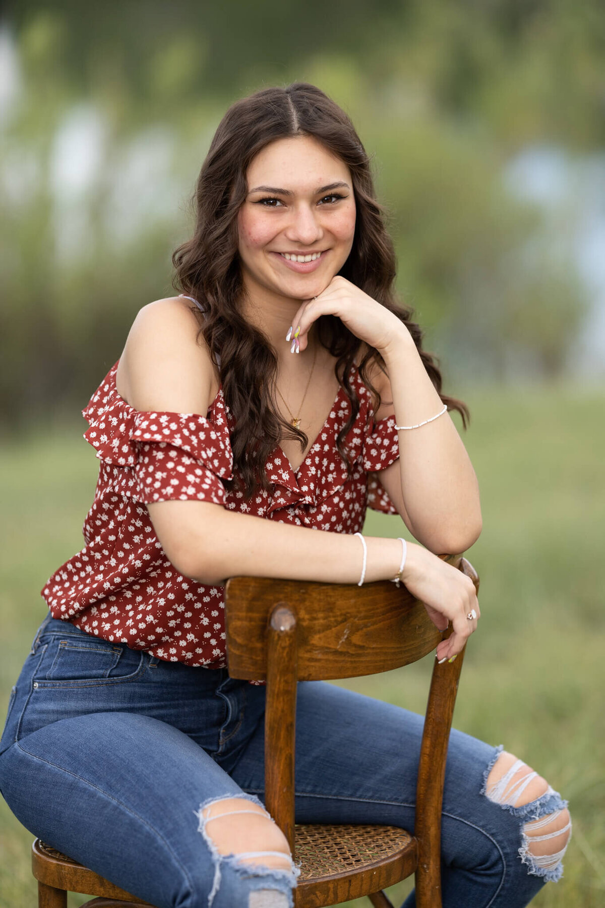 high school senior girl sitting on a chair wearing a red shirt and jeans