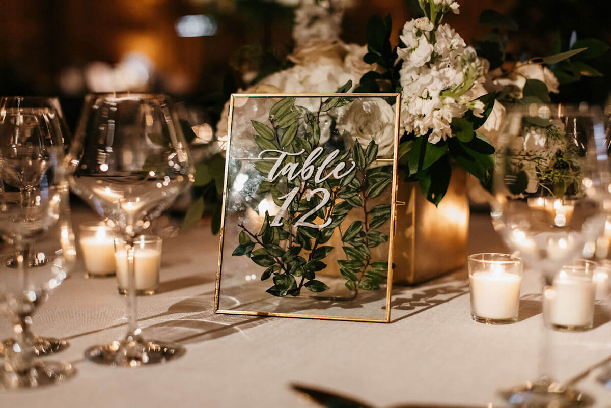 Pressed flowers in gold frame table numbers calligraphy