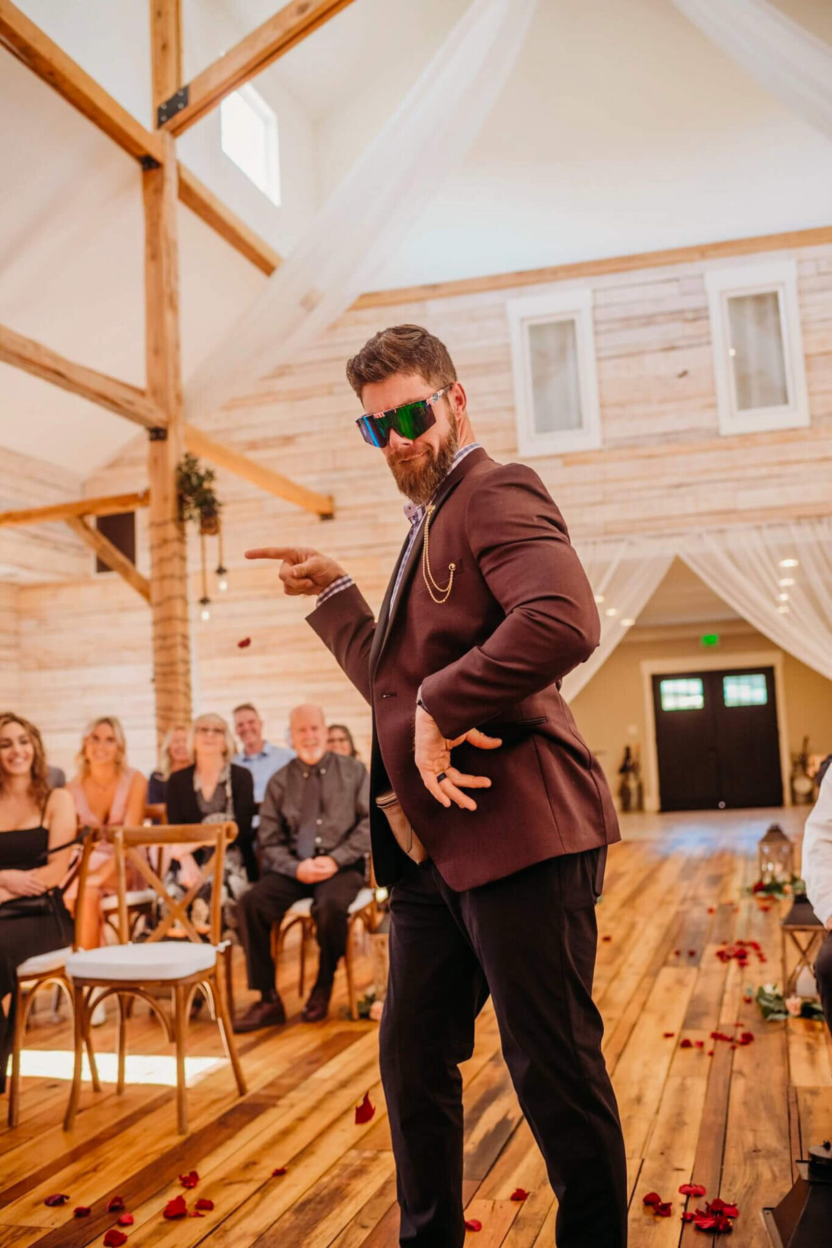 photo of a man wearing sunglasses and walking down a wedding aisle while dancing