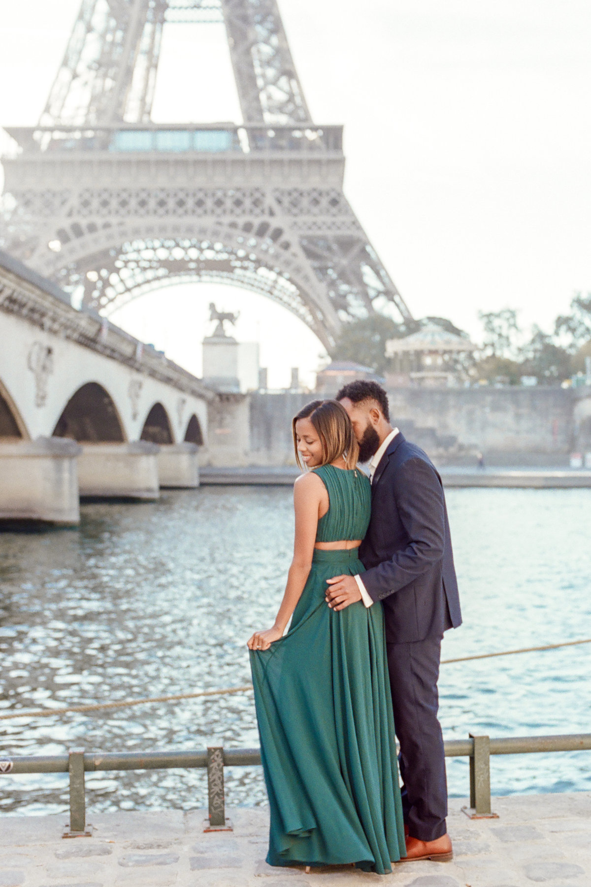 couple standing in front of seine river with eiffel tower in background