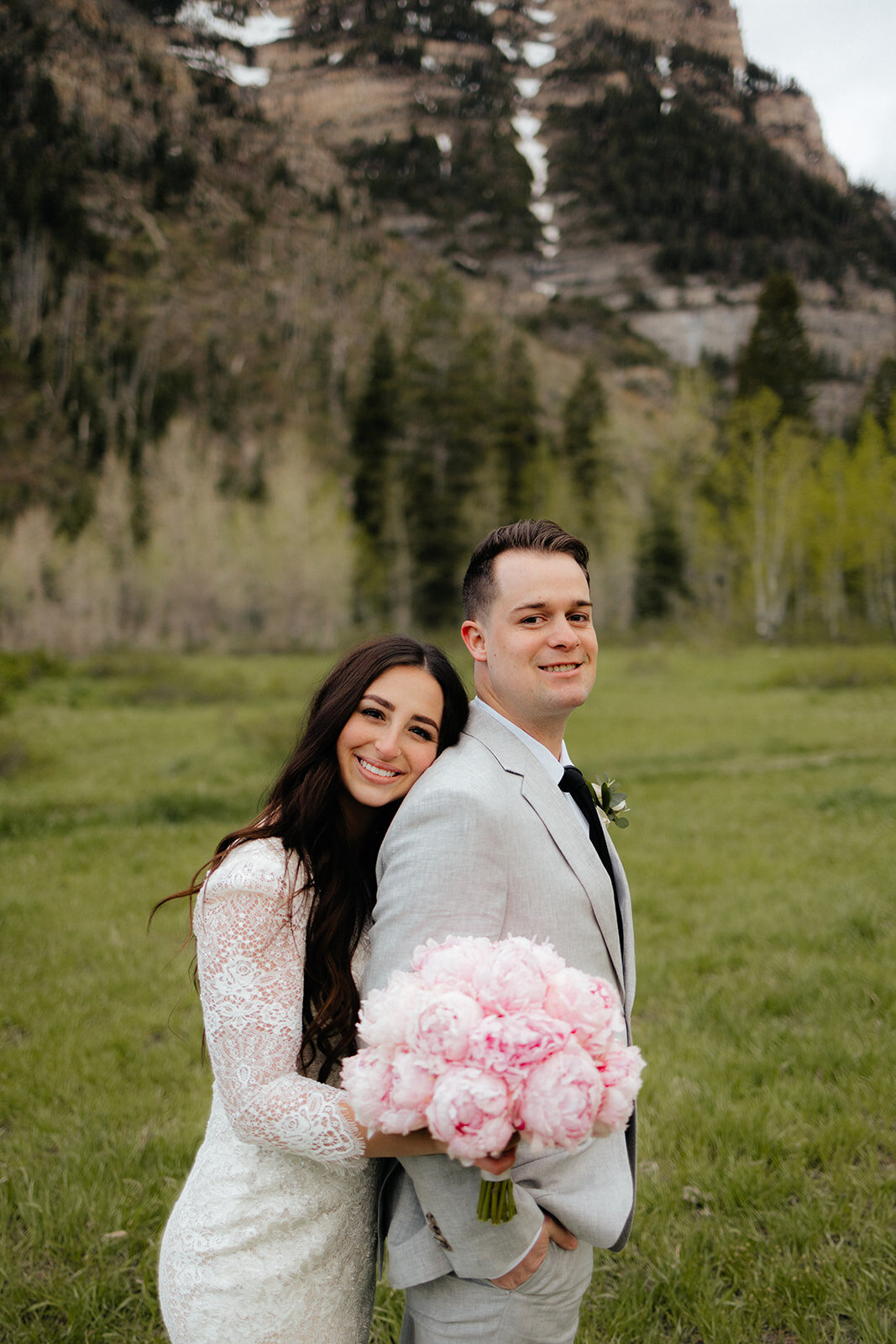 Bride and groom holding peony bouquet in the mountains.