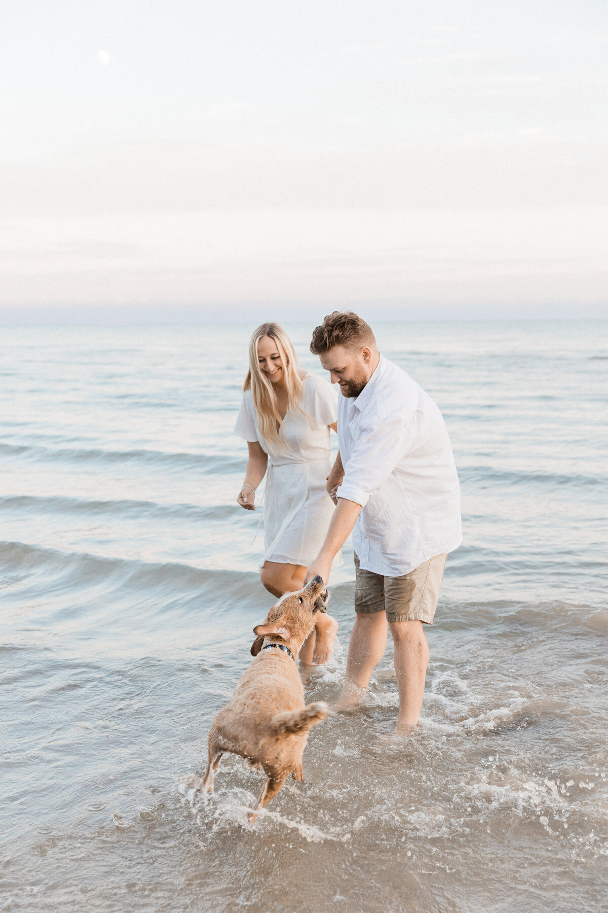 Couple playing at the beach with their dog