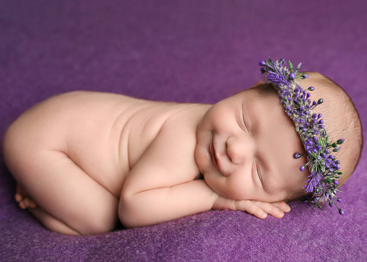 Newborn in purple floral headband sleeping