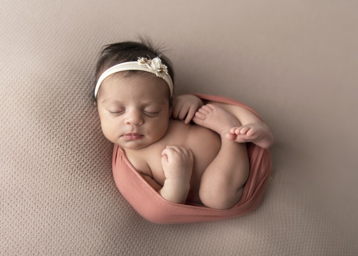 Baby girl curled up with white headband
