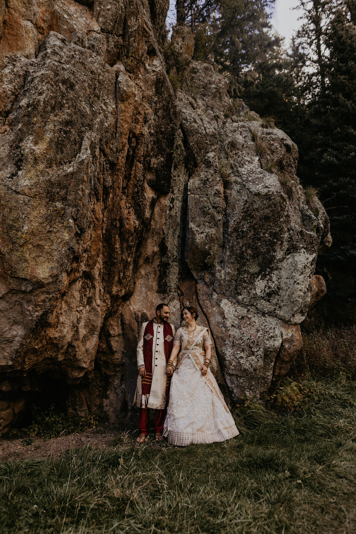 bride and groom leaning against a massive rock in New Mexico