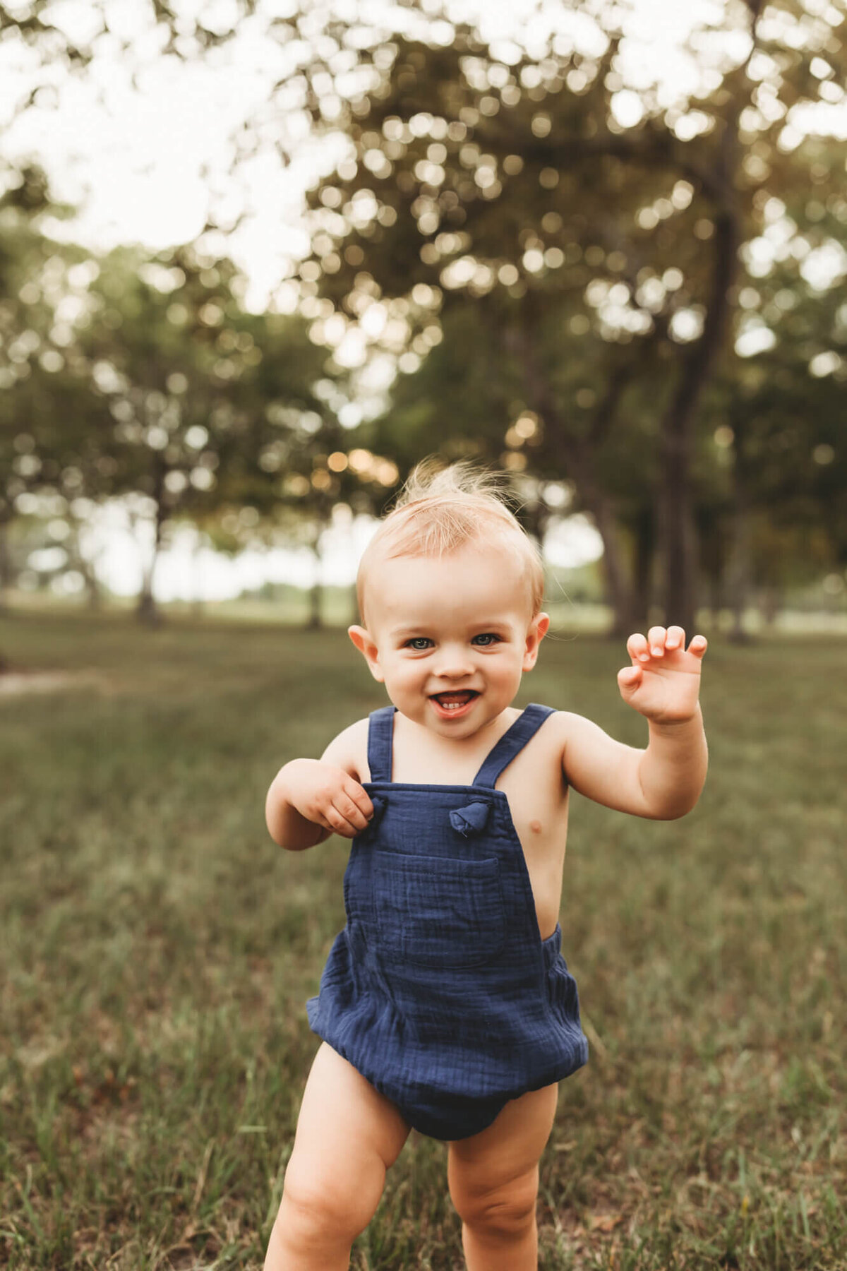 baby boy runs toward camera, wearing blue outfit for his birthday pics.