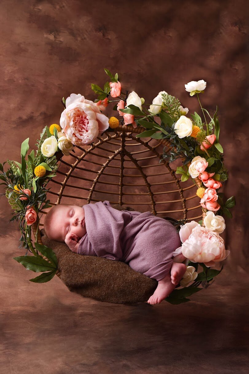 Newborn baby floating in floral hanging basket