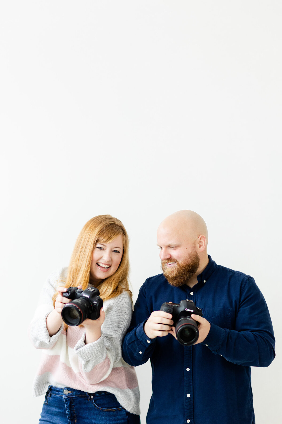 husband and wife wedding photographers posing with cameras for branding shoot