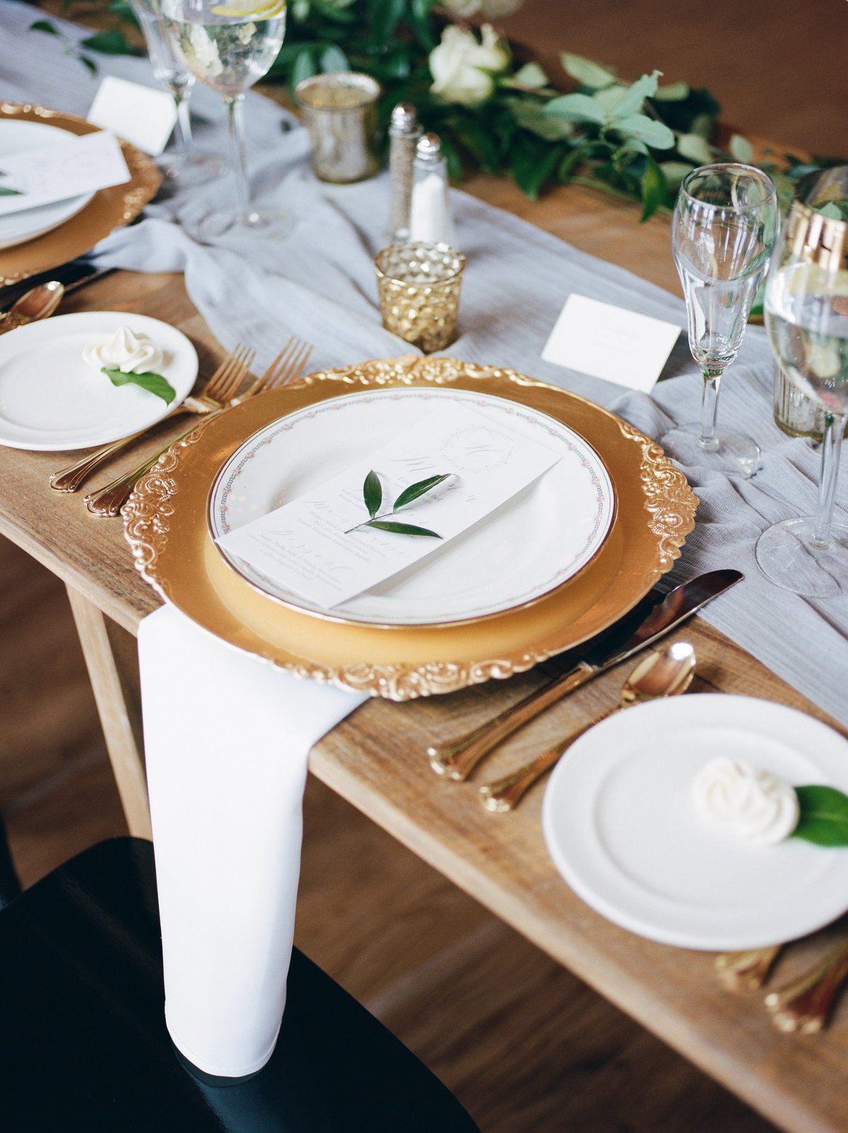 white plates with greenery on gold charger