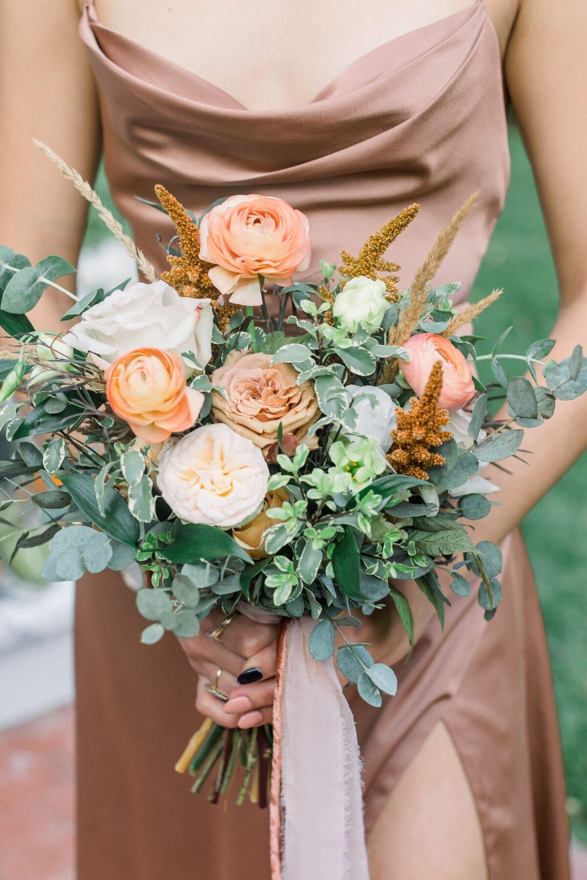 This bouquet designed by Primrose & Petals holds an array of fall colored flowers and green accents.