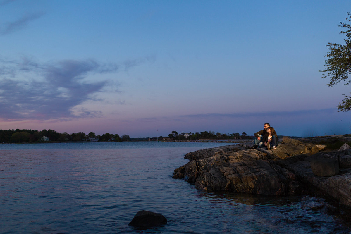 The couple sits out on the rocks for the sunset over Odiorne Point Park NH