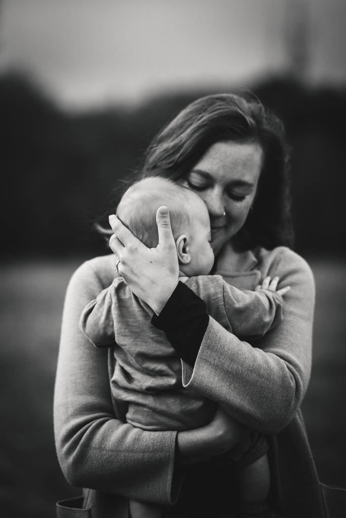 Motherhood portrait embracing baby in black and white