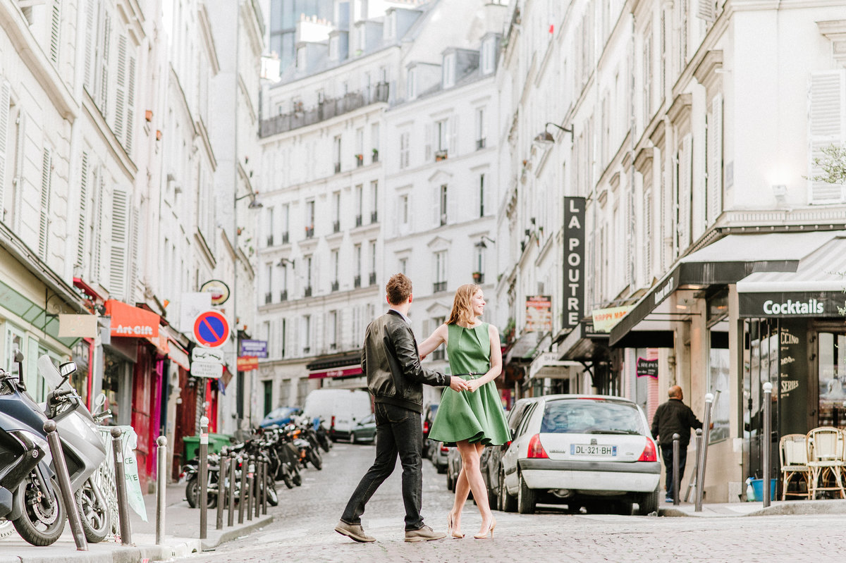 couple holding hands walking on cobblestone street in paris