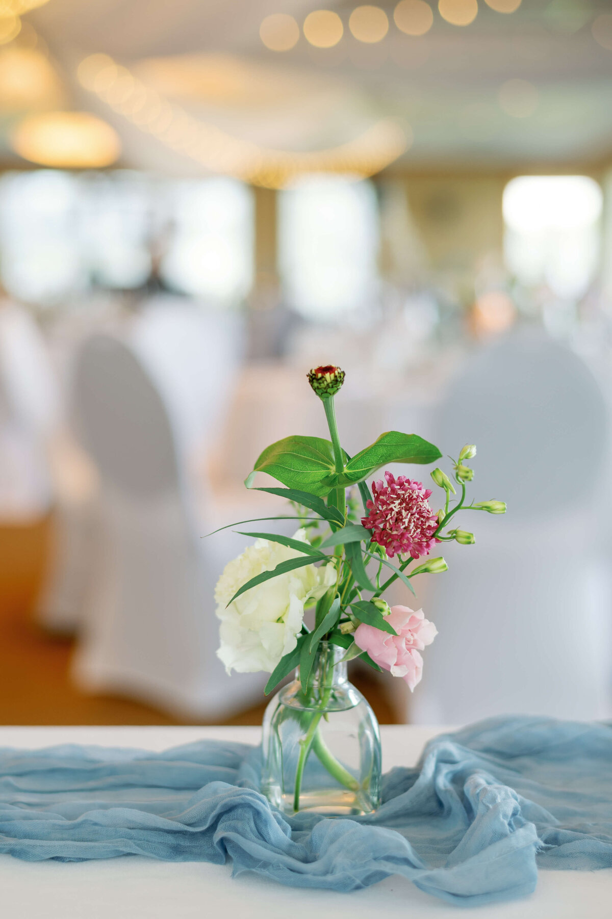 Flowers in a small vase on table with blue runner at Oak Island Resort wedding, Nova Scotia