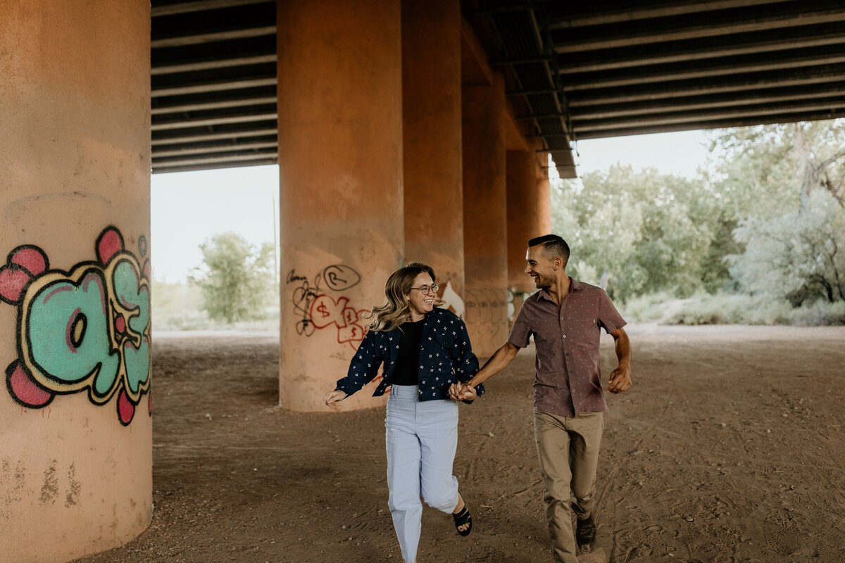 couple running together under an overpass in Albuquerque