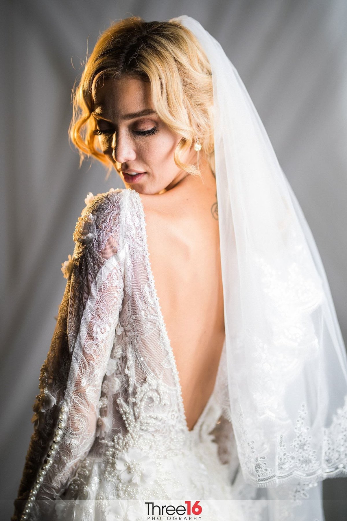 Bride looks back towards her open back wedding dress