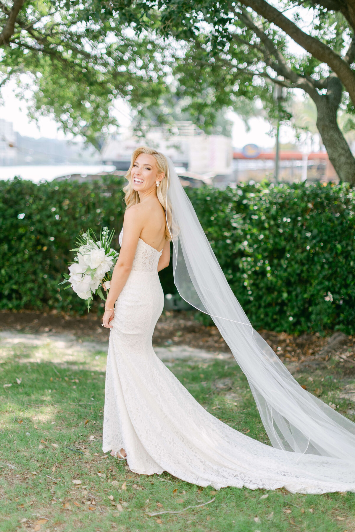 A bride walks in the grass while smiling
