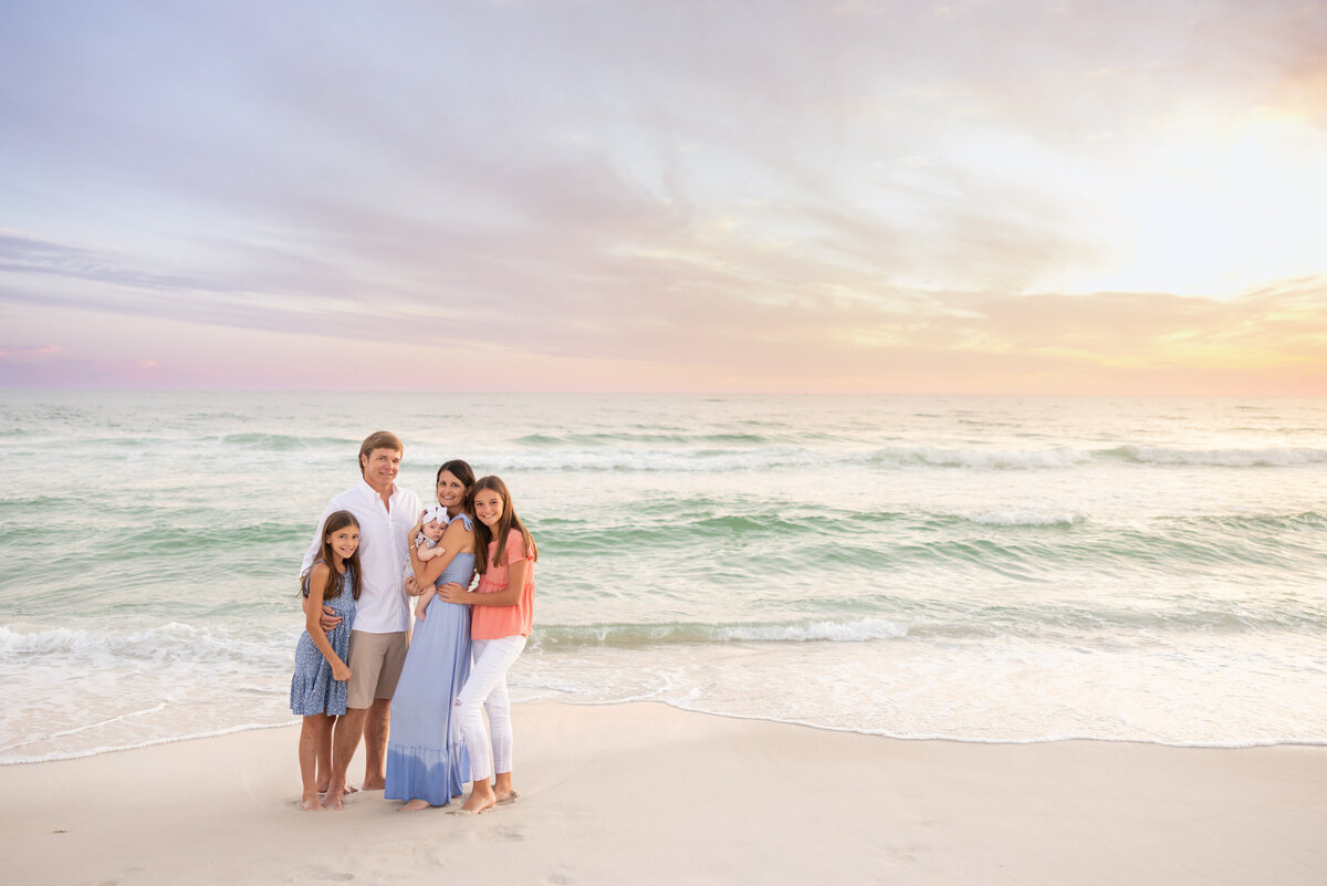 A small family standing by the water for a portrait in Rosemary Beach.