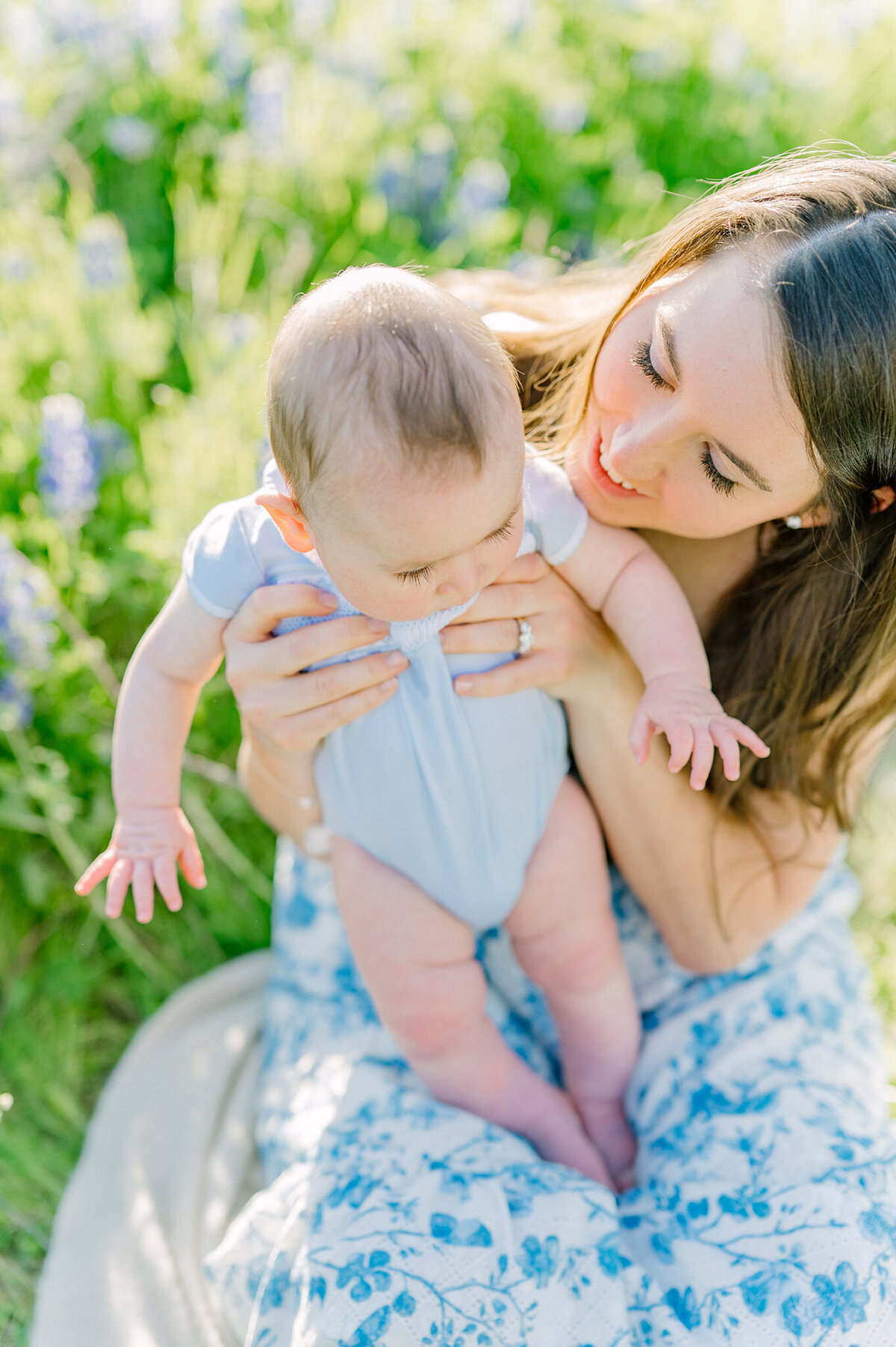 Mother palying with her baby in a field of bluebonnets.