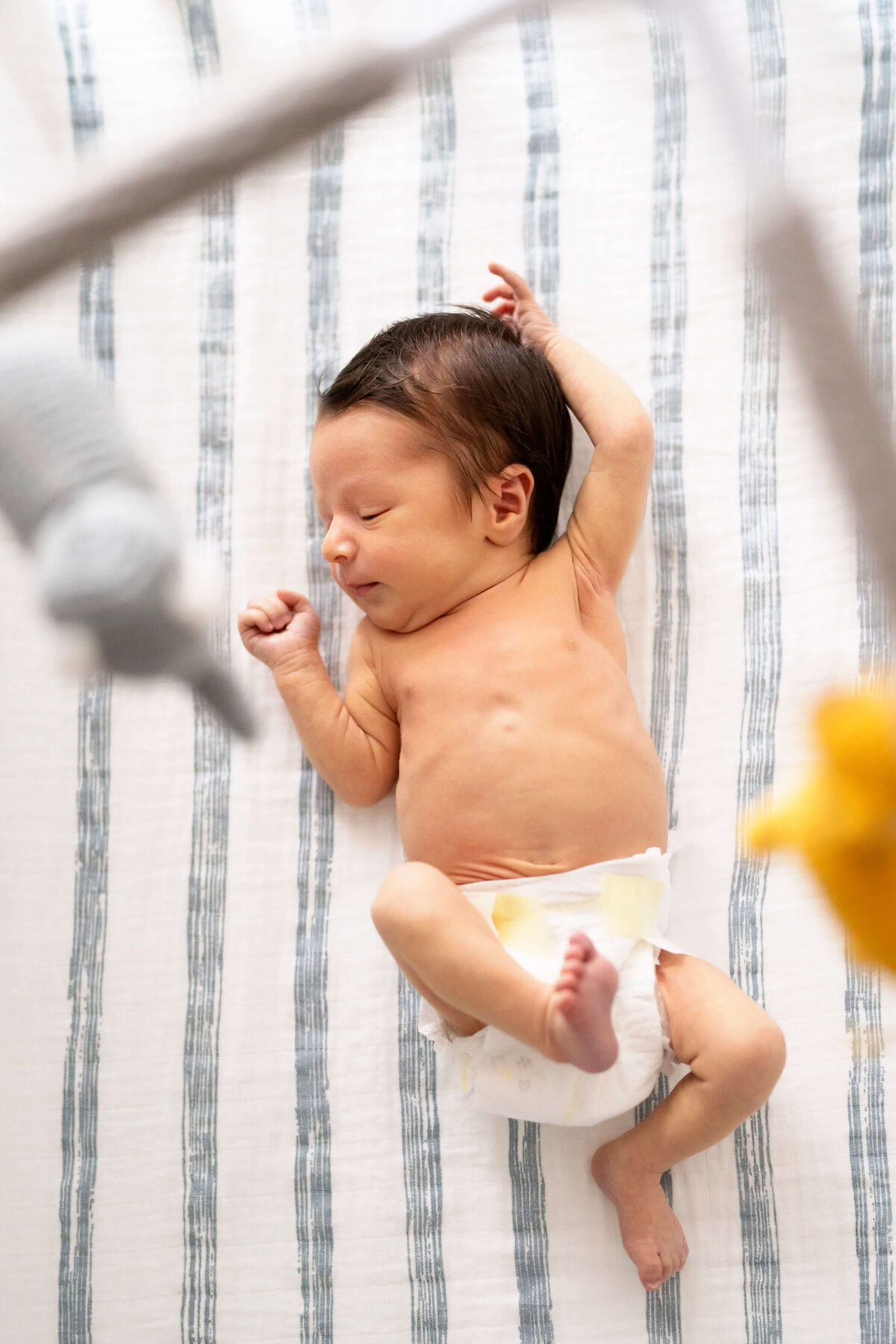 Overhead shot of newborn boy in crib shot through mobile during newborn photography session in Atlanta