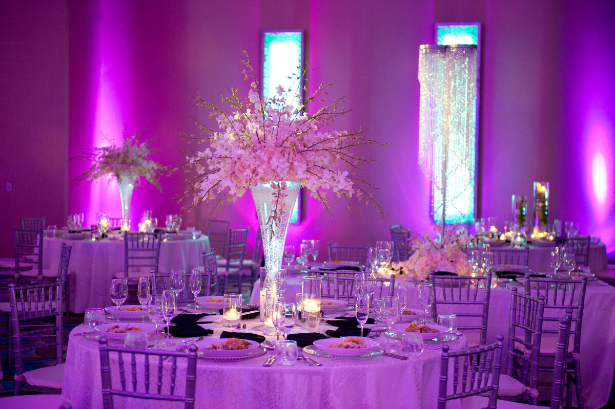 Elegant wedding reception in a hall with dinner tables, chairs and  floral centerpieces in purple theme