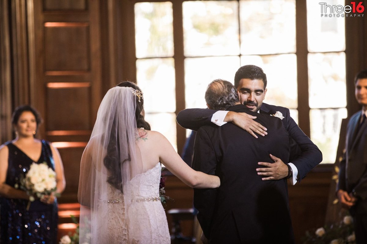 Groom hugs Bride's Father at the altar