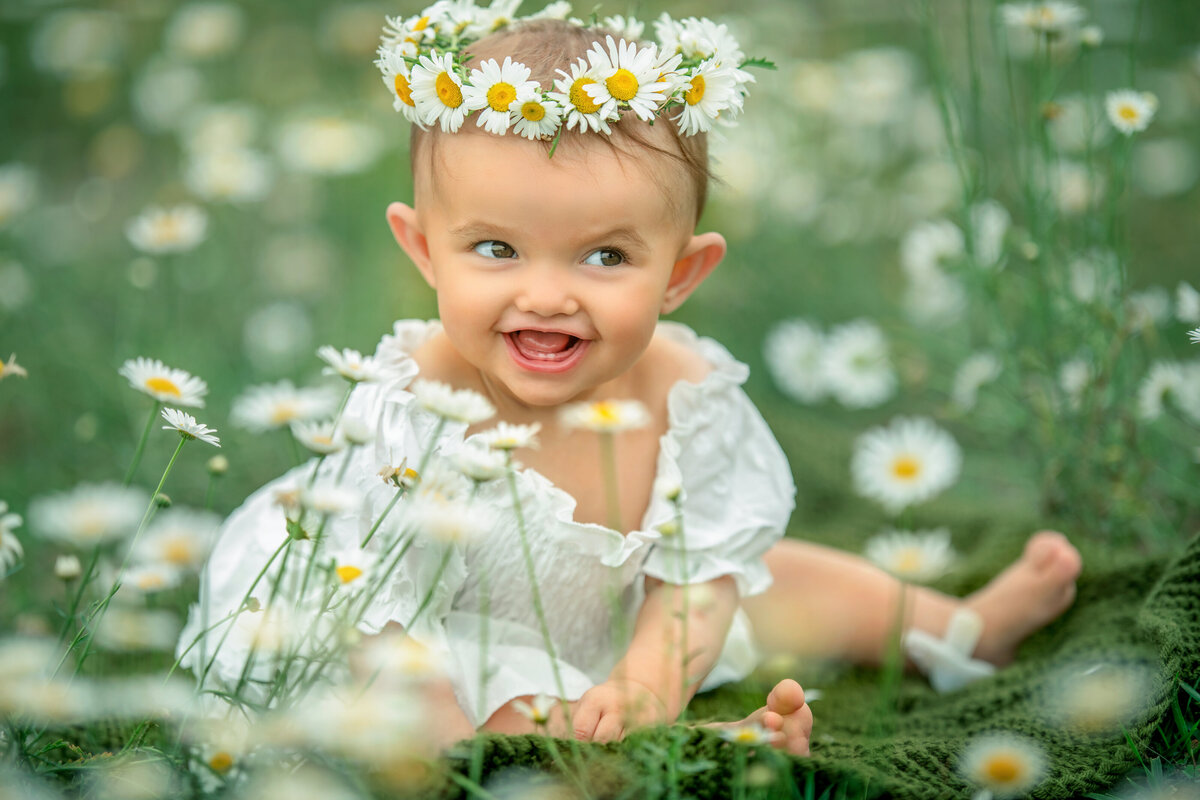 Baby girl in white dress wearing fresh daisy headband