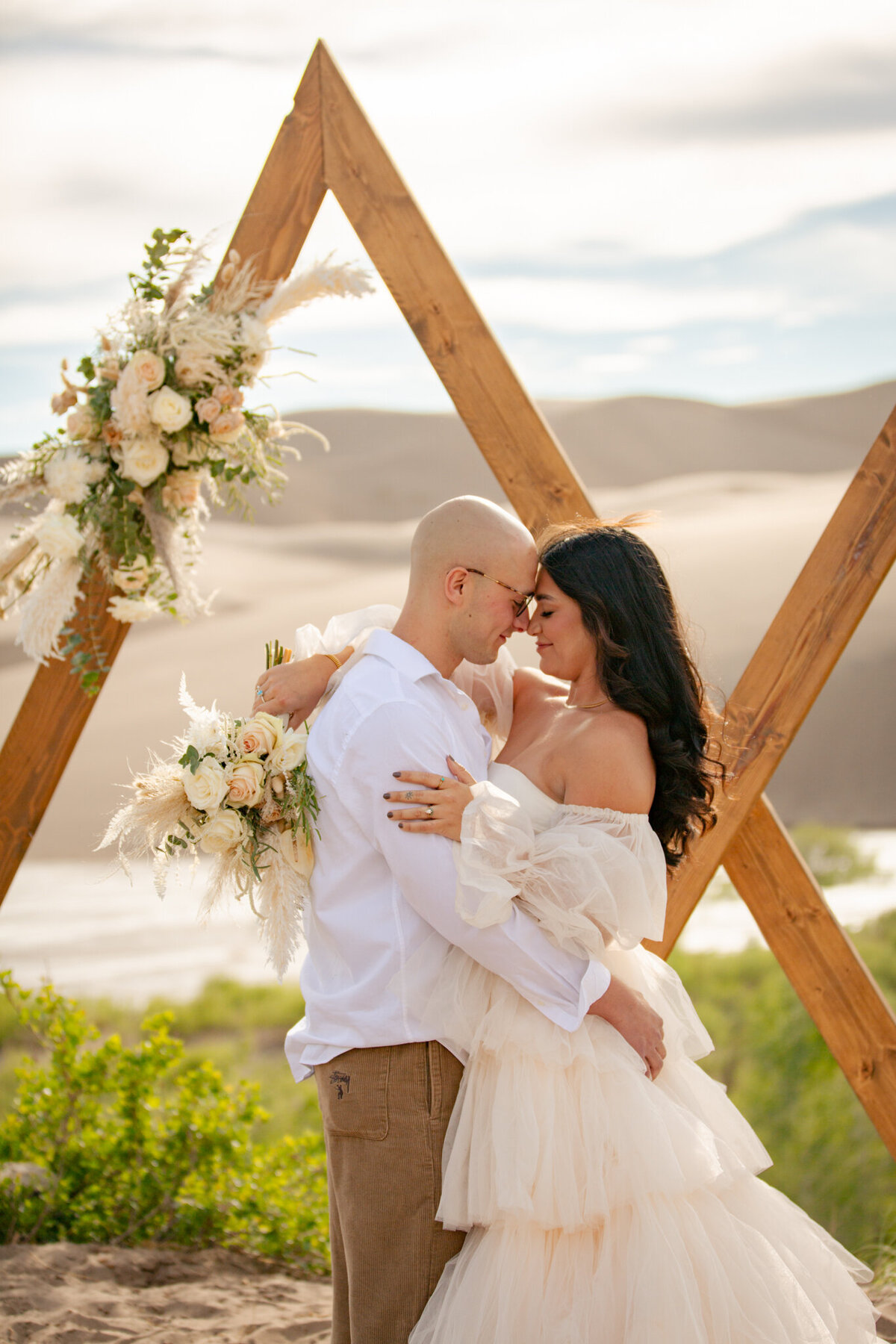 Bride and groom hold each other close during their ceremony at the sand dunes