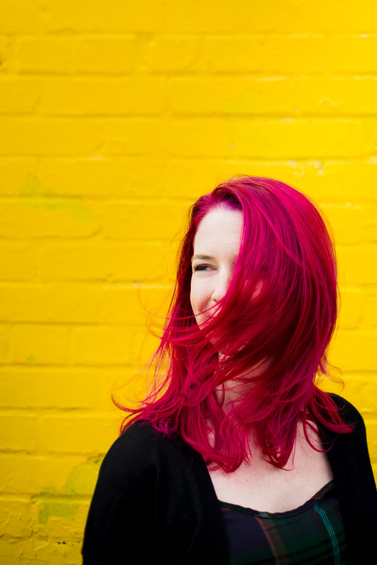 A person with red hair standing in front of a yellow wall.