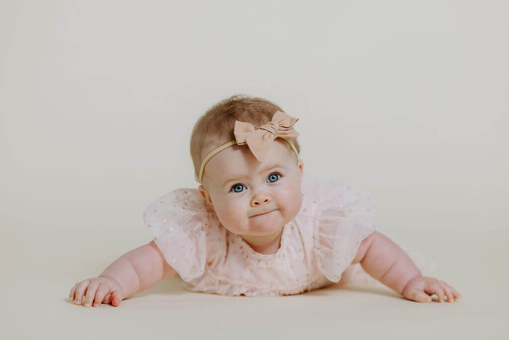 6 month portrait of baby girl in pink lace dress and bow