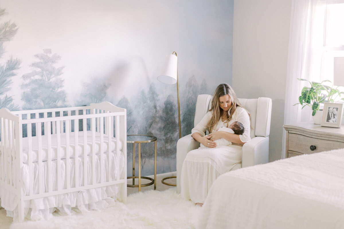 Mother holding newborn on recliner in the nursery
