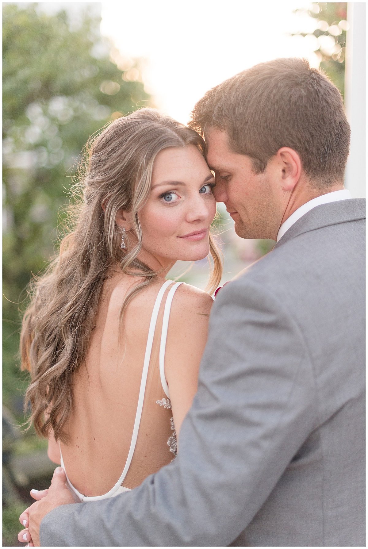 Bride looking back over right shoulder at camera as Groom rests his forehead against the side of her face in Hershey, Pennsylvania.