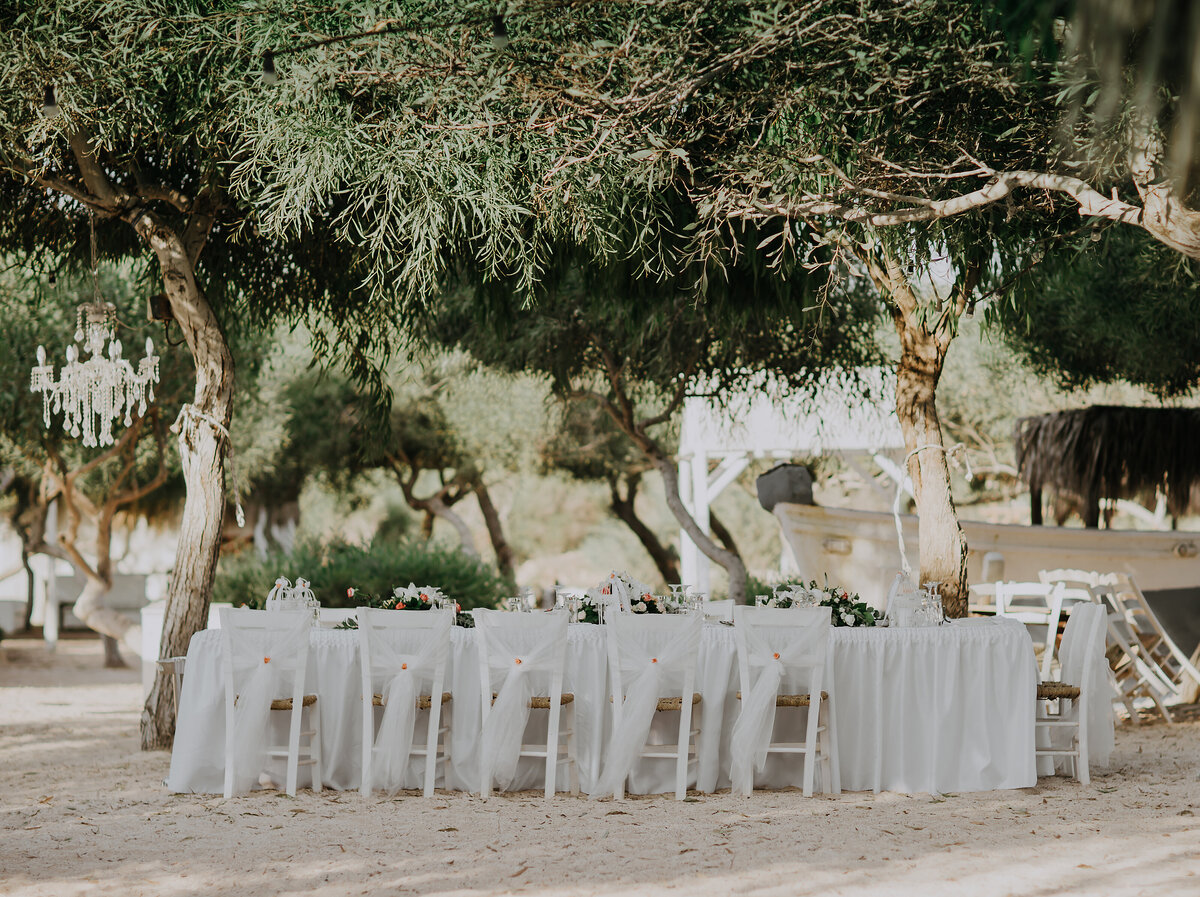 Tables sit directly on the sand on a beautiful sunny day waiting for the arrival of the wedding party