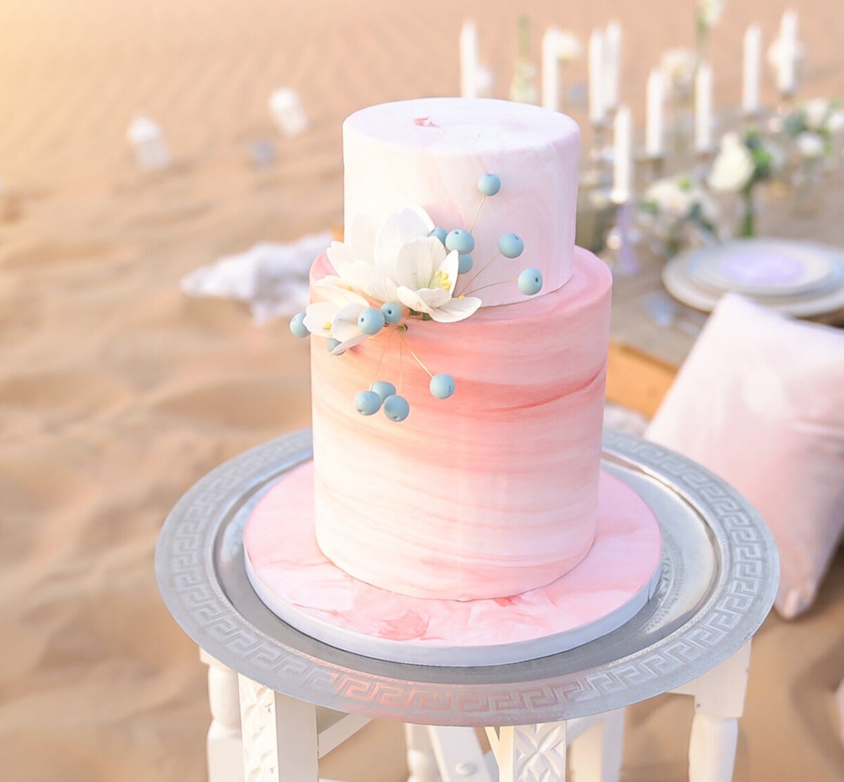 Two-tier wedding cake inspired by the movement of dunes, decorated with floral ornaments for desert elopement shoot in Dubai organized by Lovely & Planned