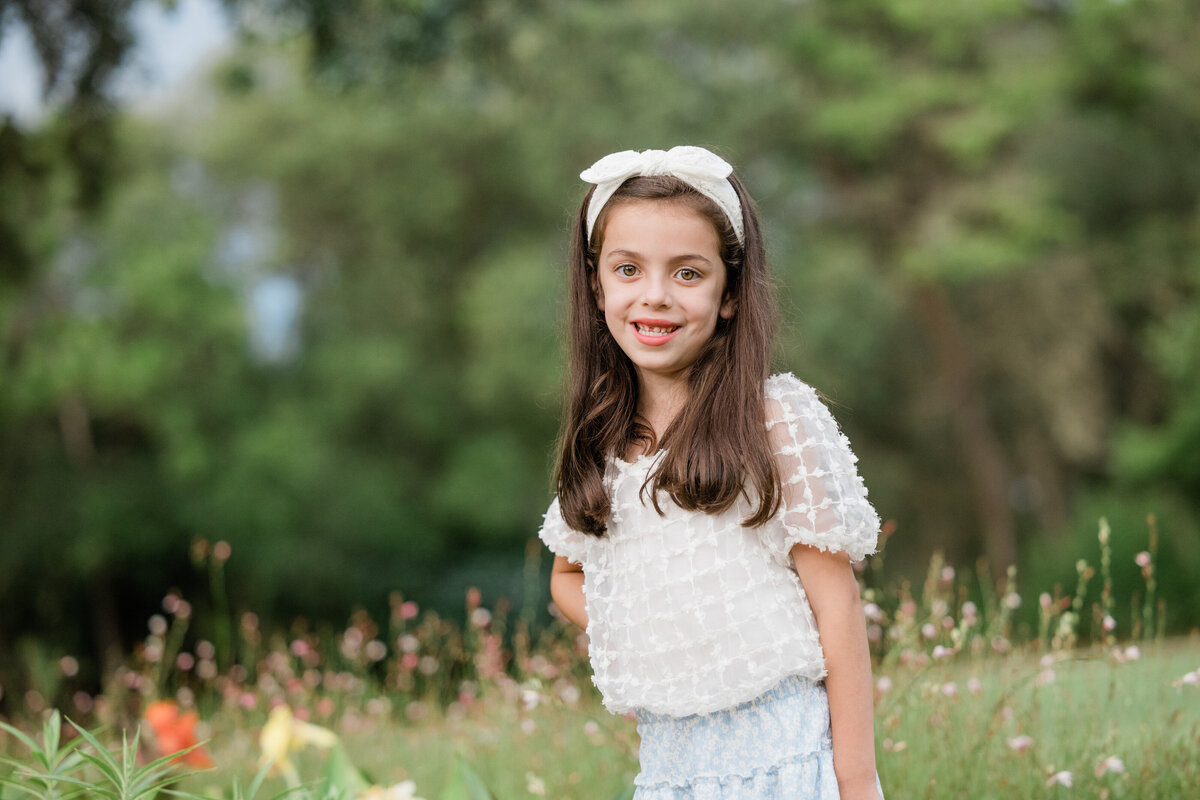 A young girl standing in tall grass smiling