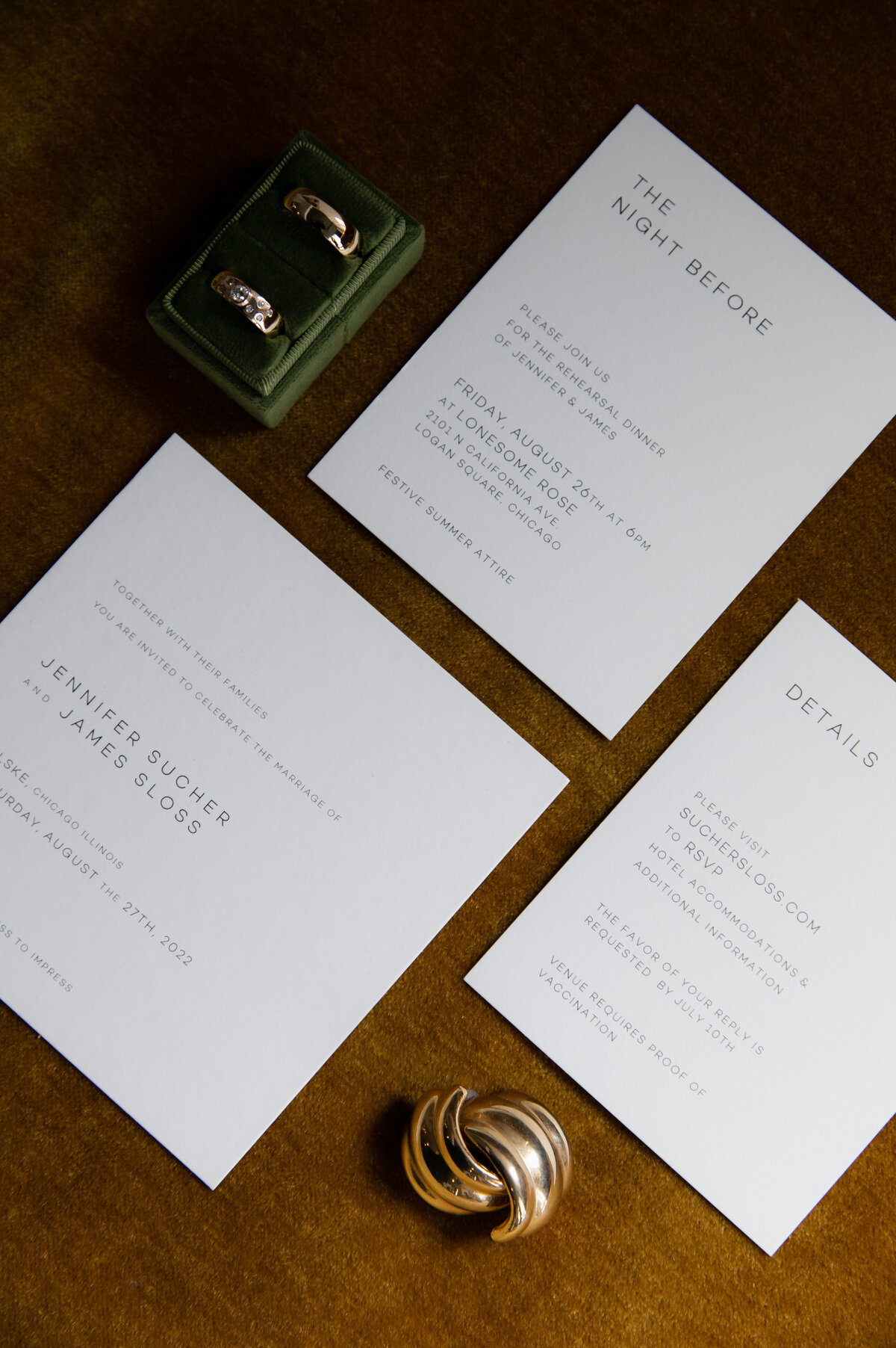 Minimalist wedding invitations, wedding bands in a green, velvet case and golden cuff links displayed on a wooden table at Chicago wedding.