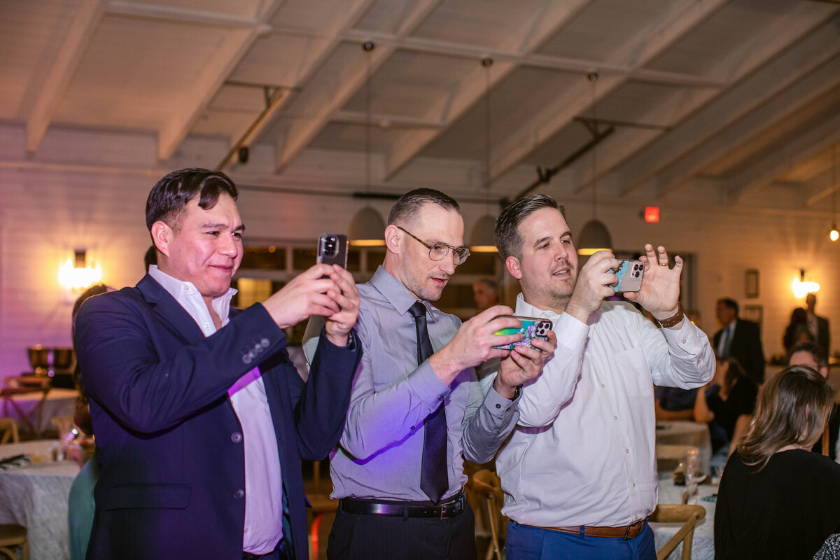 Fort worth wedding photographer captures 3 male guests taking photos of other guests on phones
