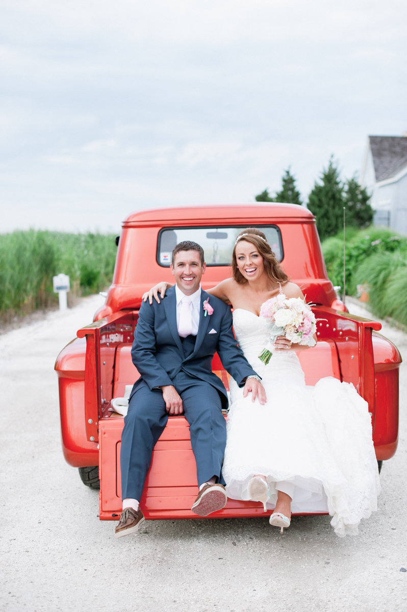 Couple just married sitting on a red Vitage red truck at bonnet Island Estate