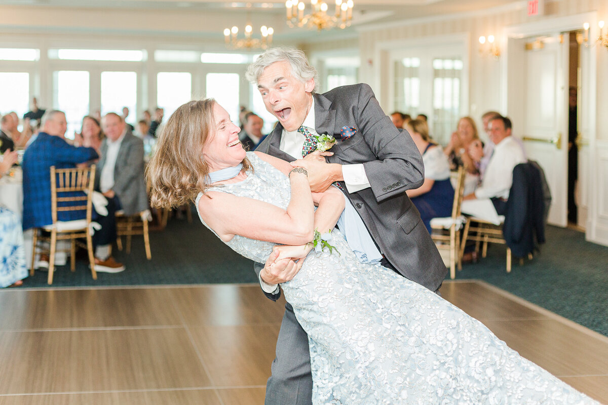 Bride's parent's share a fun dance as the father of the bride dips the mother of the bride. Both are laughing. Captured at a Madison Beach Hotel wedding receiption. Captured by best New England wedding photographer Lia Rose Weddings.