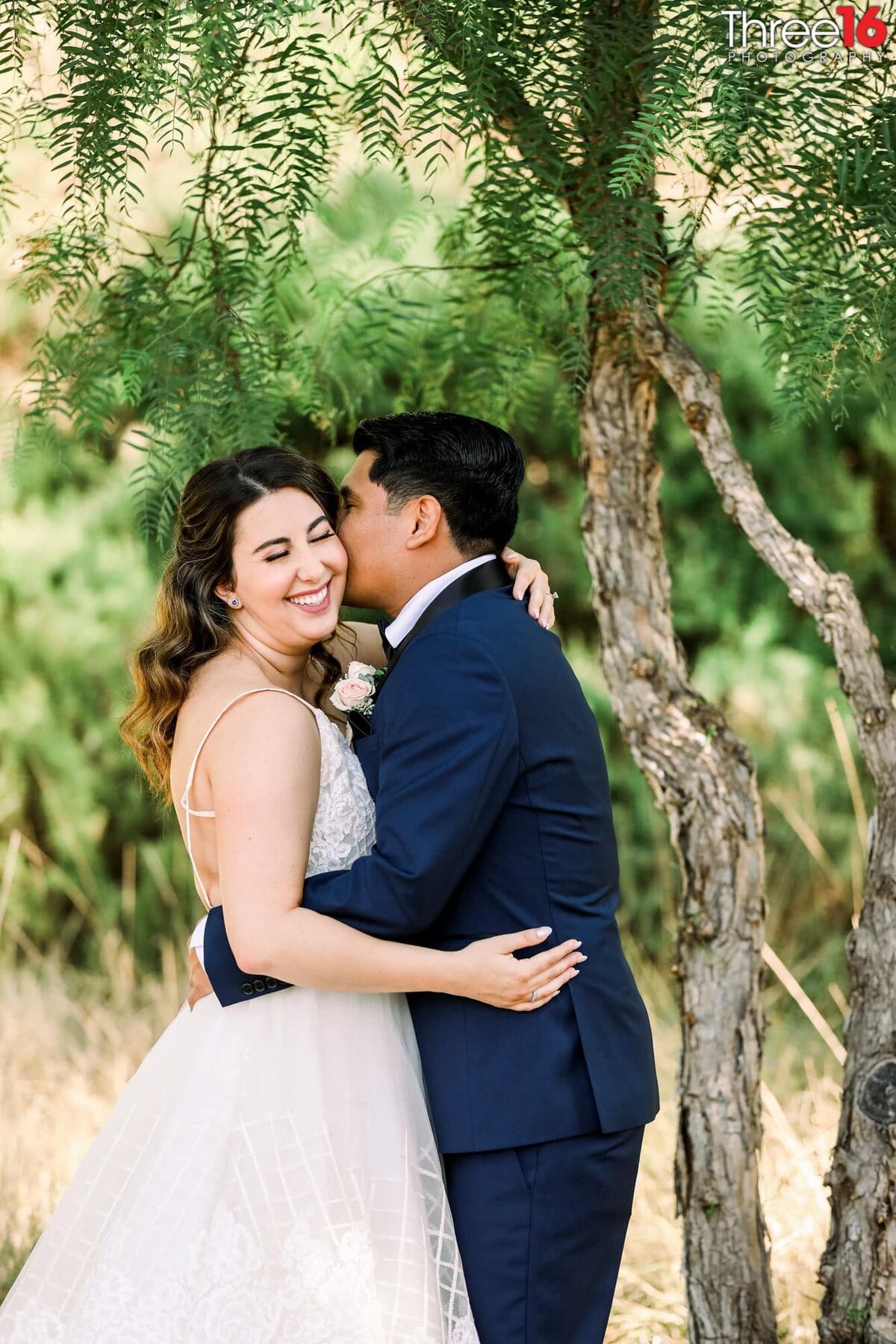 Groom whispers into his Bride's ear causing her to have a big smile as the hold each other
