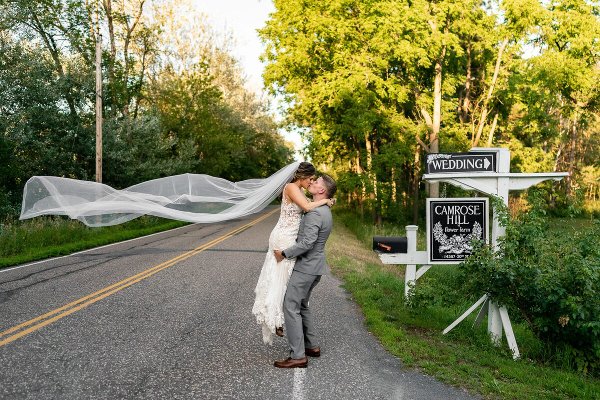 Groom lifts and kisses bride in the road in Stillwater, Minnesota.