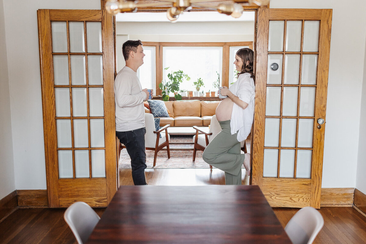 Pregnant woman and husband standing in doorway having a chat