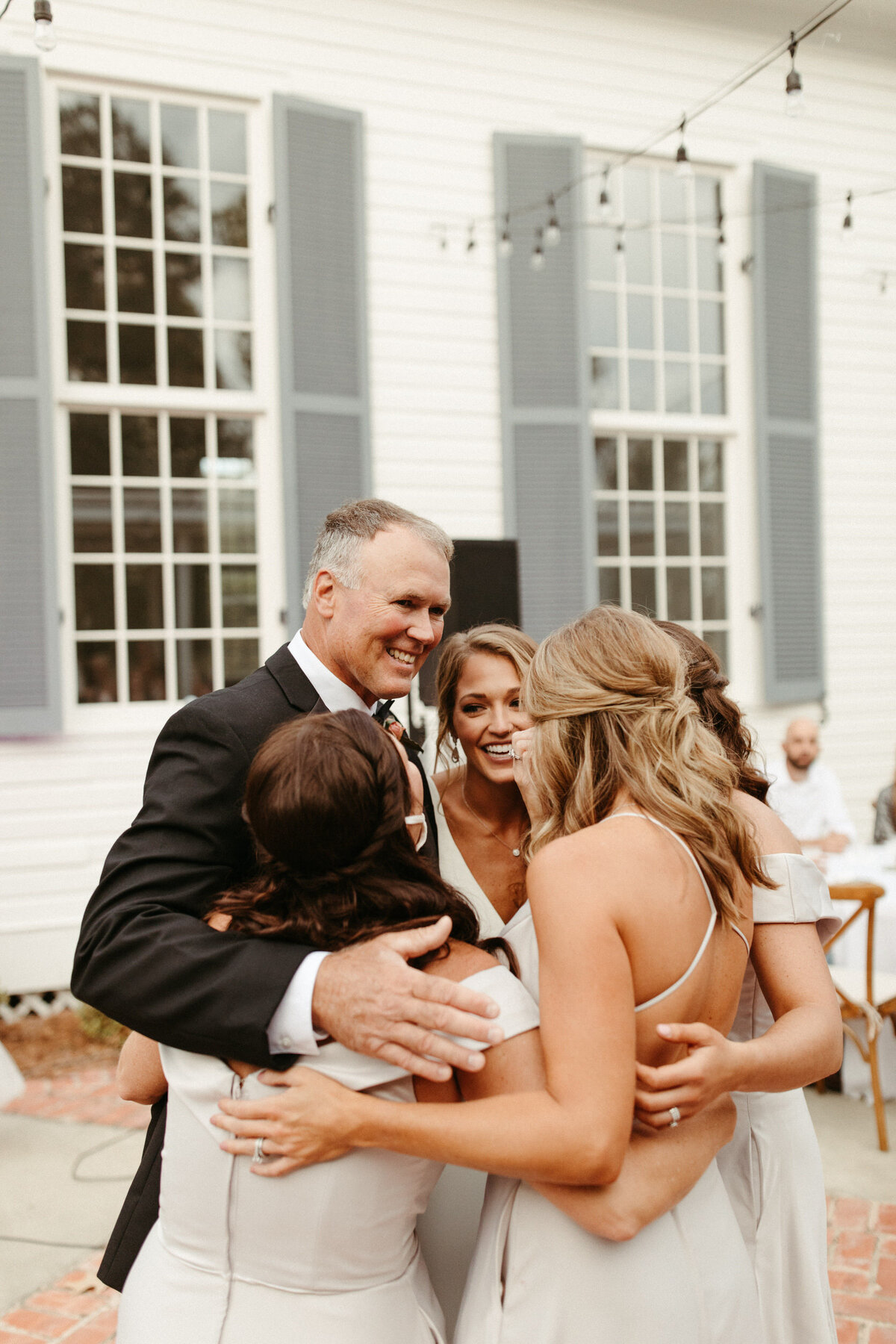 Sweet family moment of a bride dancing with her parents and sisters