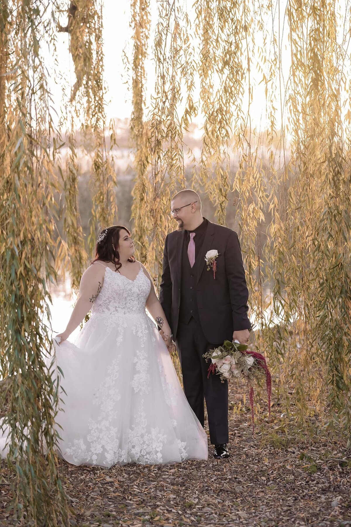 bride and groom looking at each other under a weeping willow