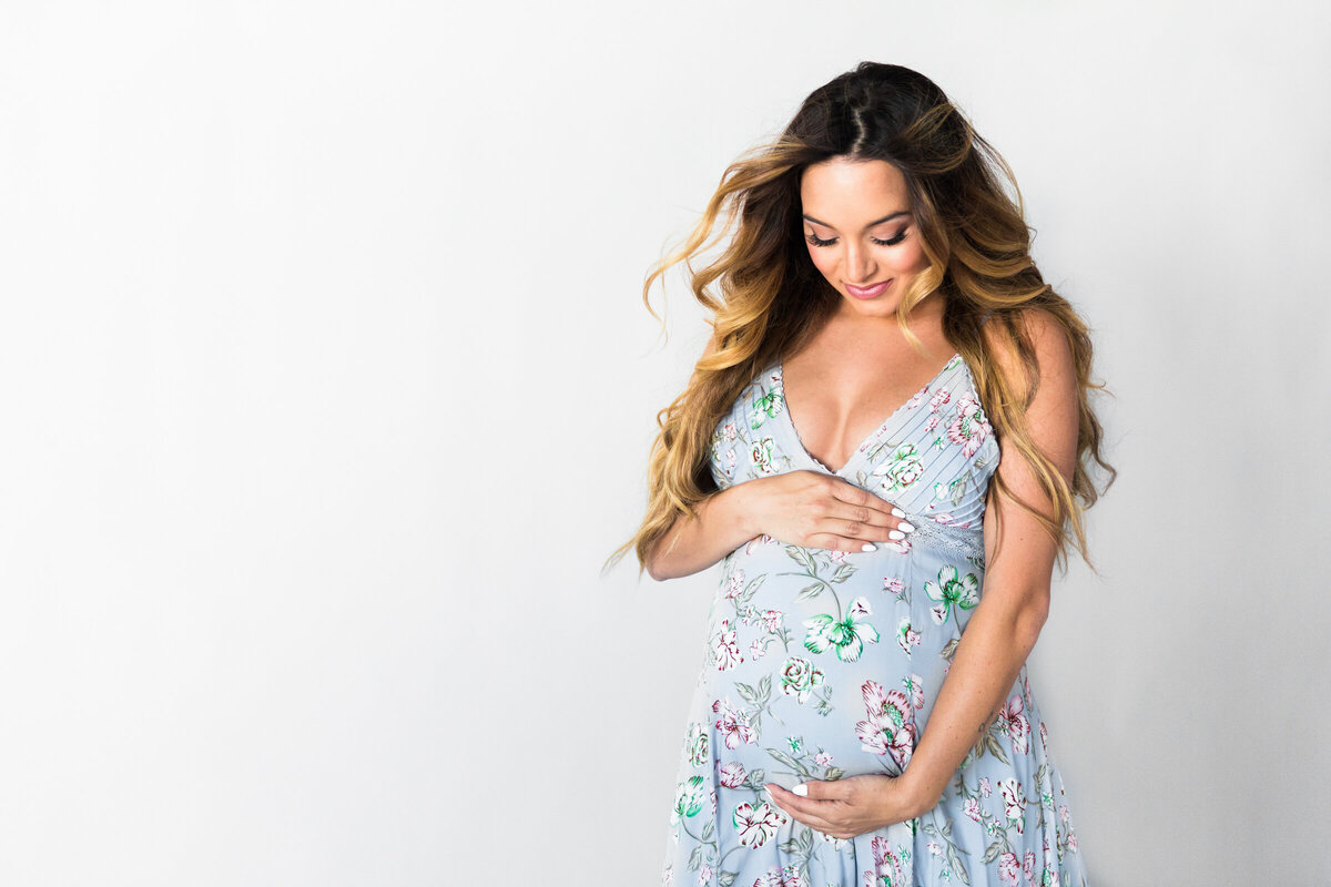 pregnant woman holding baby bump for studio maternity photography session
